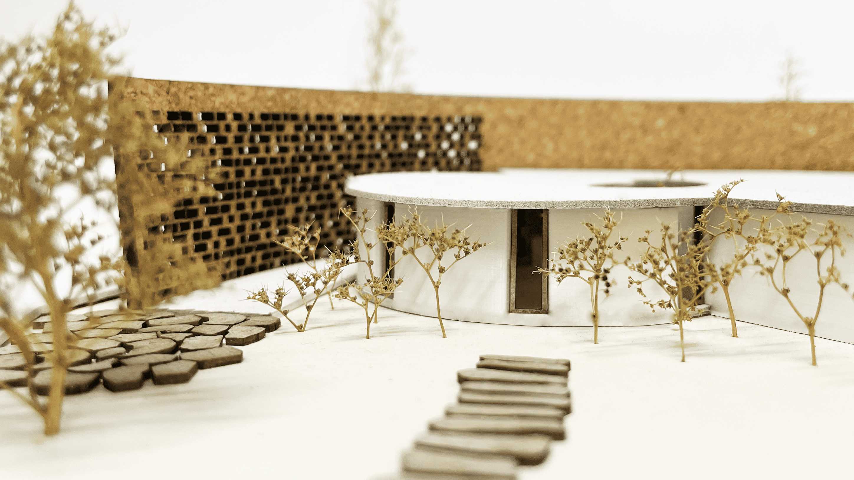 Zoomed in view of main entrance featuring a curved building shape, a textured brick privacy wall, and natural landscape features to provide a tranquil setting that encourages rest and reflection.