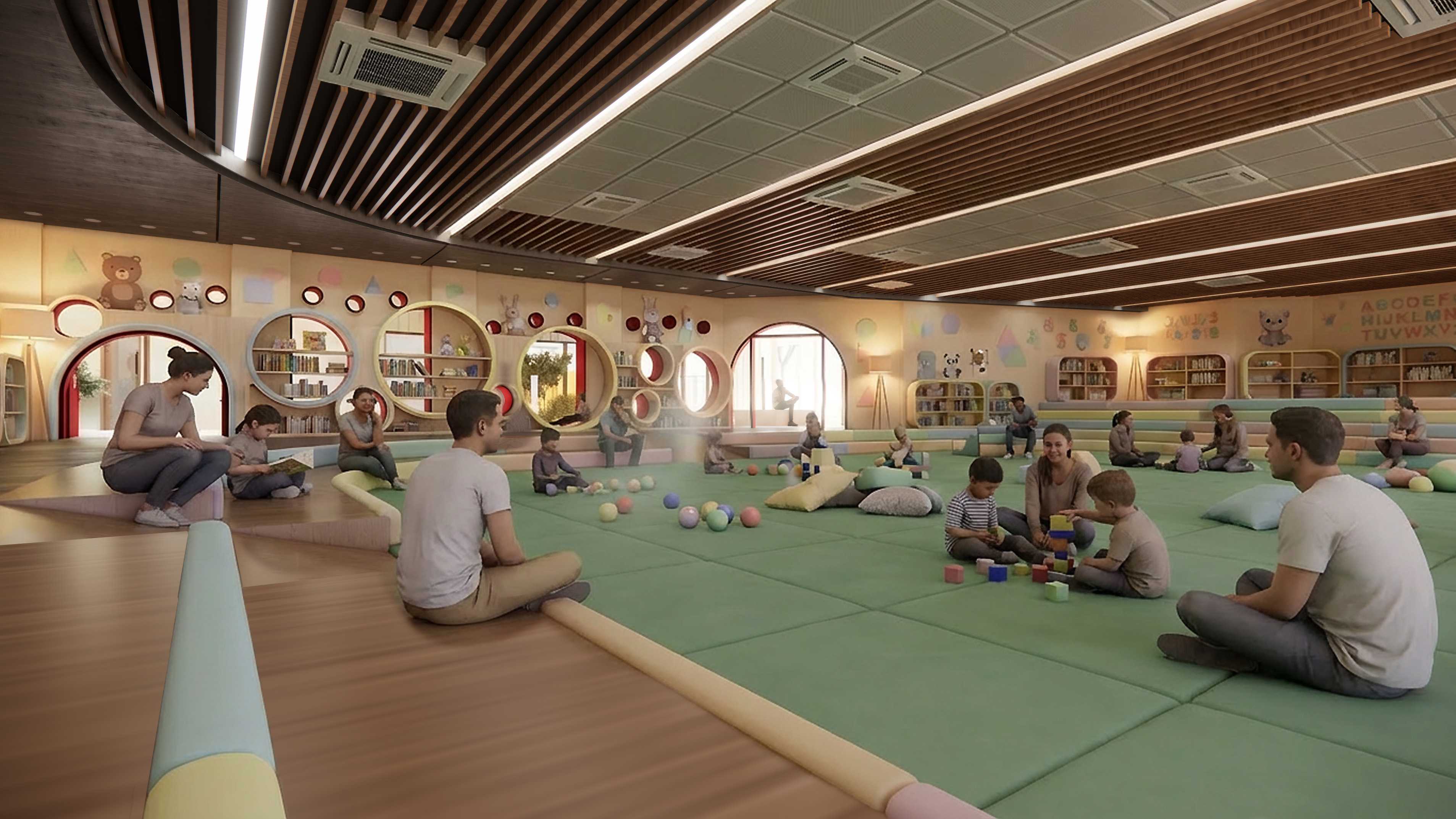 Parents and children play on soft green mats, surrounded by gentle light, warm timber tones, and scattered toys—an airy, cushioned space offering cool, relaxed comfort despite the heat outside.