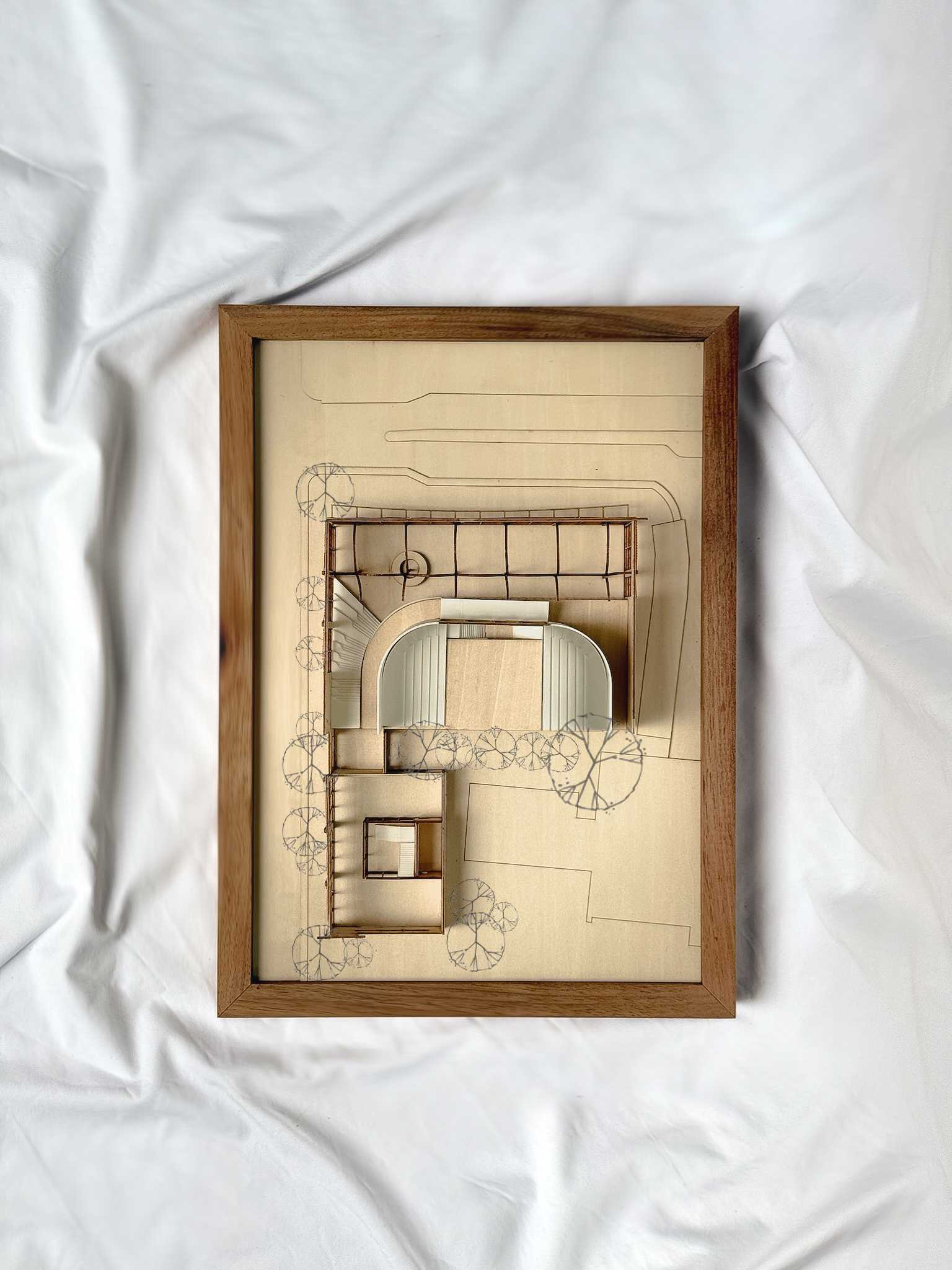 A model photograph in plan, illustrating the overall composition within the existing trees and the university’s main-road entrance.